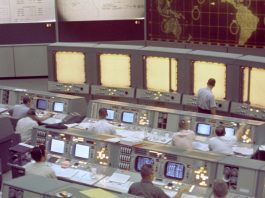 Overall view of the Mission Control Center (MCC), Houston, Texas, during the Gemini 5 flight. Note the screen at the front of the MCC which is used to track the progress of the Gemini spacecraft.