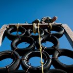 Man scaling a barrier on an assault course