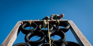 Man scaling a barrier on an assault course