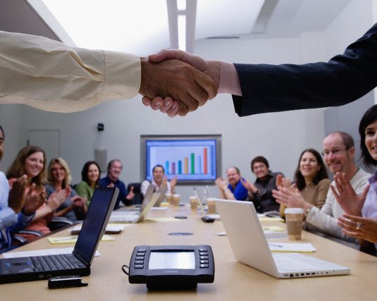 Two people shaking hands in a meeting
