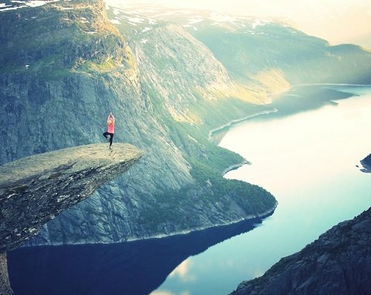 A person doing yoga poses on a cliff