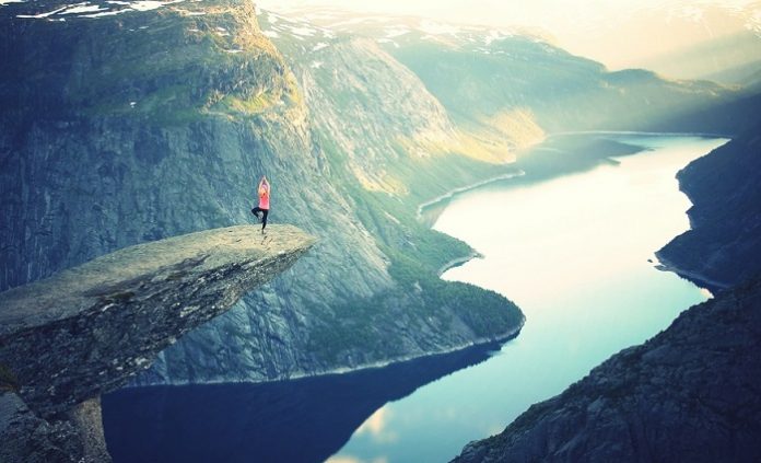 A person doing yoga poses on a cliff